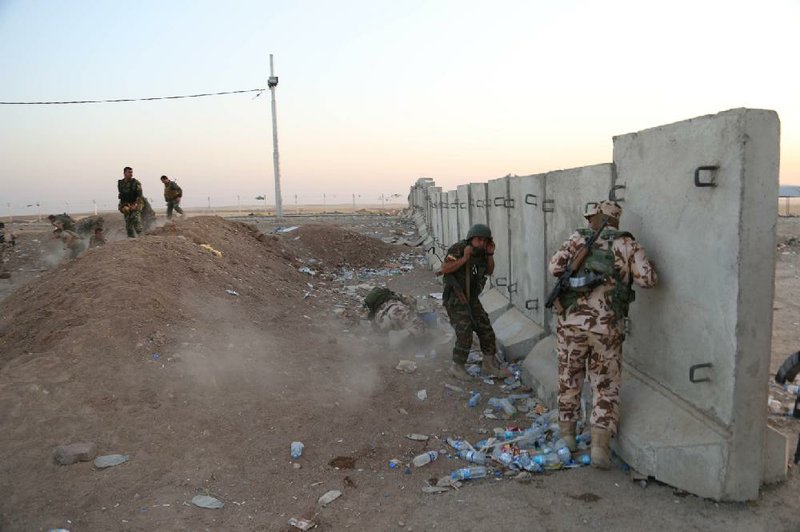 Kurdish peshmerga fighters take cover Friday during airstrikes on Islamic militants near the Khazer checkpoint outside Irbil in northern Iraq.