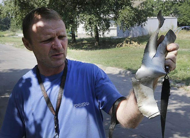 A local resident displays fragment of a shell after shelling in Donetsk, eastern Ukraine, Friday, Aug. 8, 2014. At least three civilians have been killed and another 10 wounded in overnight shelling of the main rebel stronghold in eastern Ukraine besieged by government forces, officials said. (AP Photo/Sergei Grits)