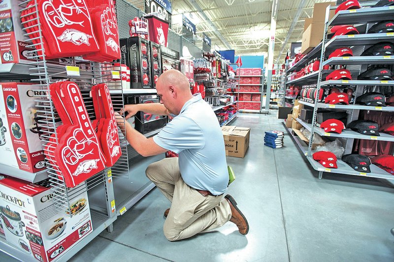 STAFF PHOTO ANTHONY REYES &#8226; @NWATONYR David Finch, merchandise supervisor, stocks shelves Friday in the Razorbacks fan section of the new store in Springdale.