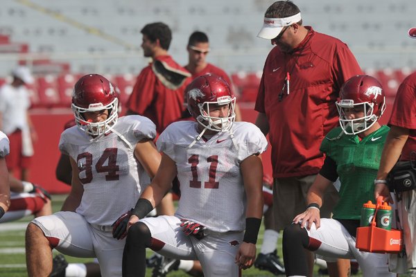 Arkansas coach Bret Bielema talks with his players Hunter Henry, AJ Derby and Brandon Allen as they warm up for practice Saturday, Aug. 9, 2014, at Razorback Stadium in Fayetteville.