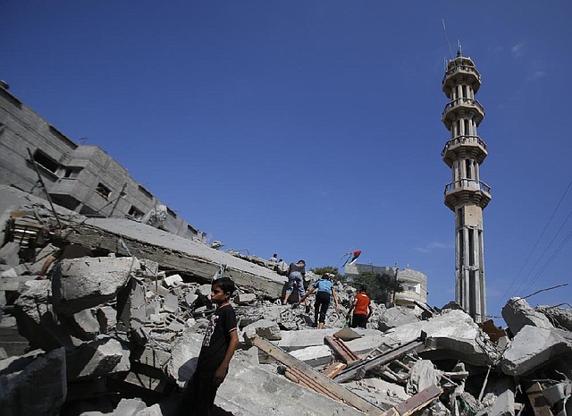 Palestinians stand in rubble of the al-Qassam mosque in Nuseirat refugee camp, central Gaza Strip, after it was hit by an Israeli airstrike, Saturday, Aug. 9, 2014. (AP Photo/Hatem Moussa)