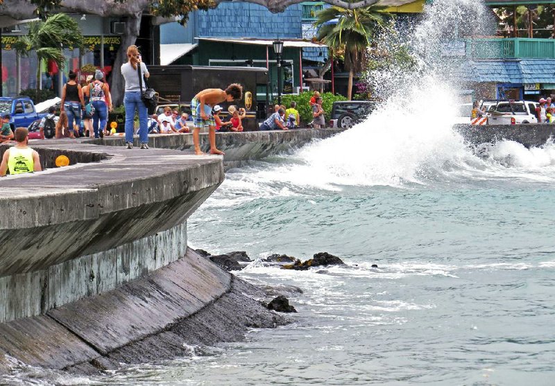 Visitors at the Ali’i Drive seawall watch large storm-driven waves in Kailua-Kona on the island of Hawaii, Friday, Aug. 8, 2014. Iselle, the first tropical storm to hit the state in 22 years, knocked out power, caused flooding and downed trees when it crossed onto the Big Island in a rural and sparsely populated region. (AP Photo/Chris Stewart)