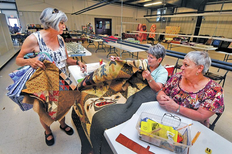 STAFF PHOTO BEN GOFF &#8226; @NWABenGoff Linda Hancock, from left, of Bentonville, drops off four quilted items entries Saturday with volunteers Judy Bell, of Rogers, and Shirley Sands, of Cave Springs at the Benton County Fairgrounds.