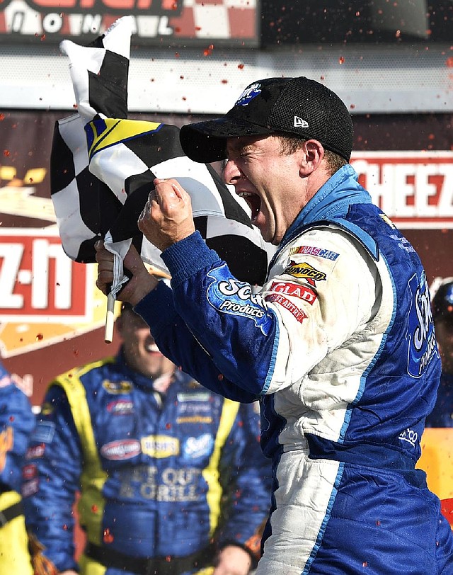 AJ Allmendinger waves the checkered flag as he celebrates in Victory Lane after winning a NASCAR Sprint Cup Series auto race at Watkins Glen International, Sunday, Aug. 10, 2014, in Watkins Glen, N.Y. (AP Photo/Derik Hamilton)