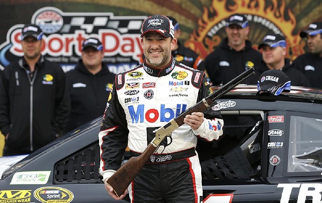 Tony Stewart poses with pole prize rifle after he took the pole position for the NASCAR Sprint Cup Series auto race at Texas Motor Speedway in Fort Worth, Texas, Saturday, April 5, 2014. (AP Photo/LM Otero)