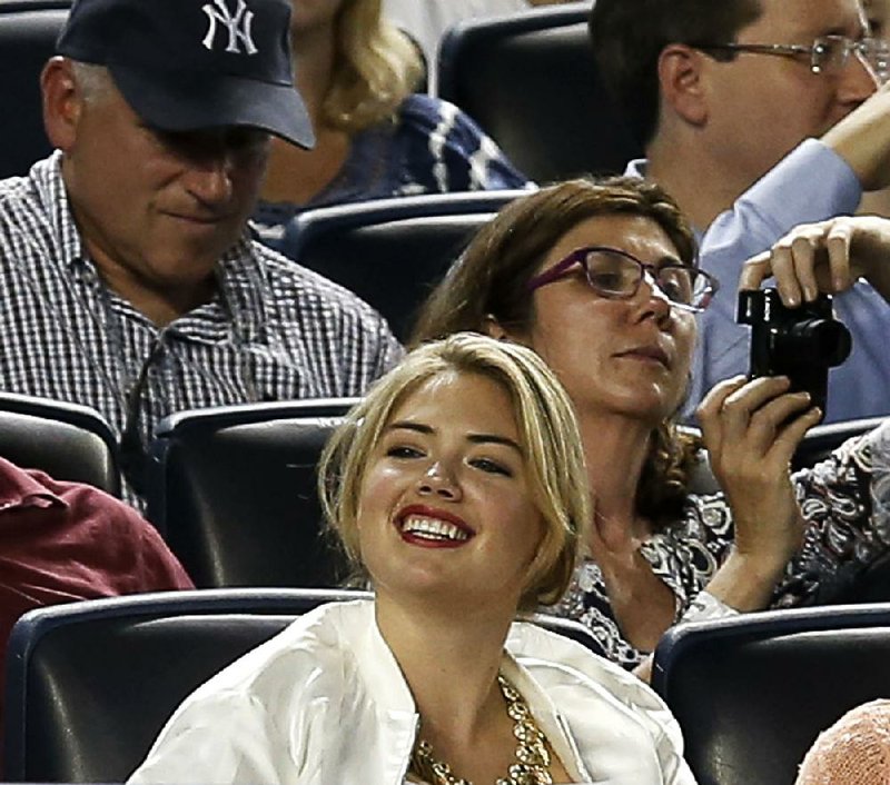 Supermodel Kate Upton smiles as she sits in the seats above the Detroit Tigers dugout in a baseball game between the Tigers and the New York Yankees at Yankee Stadium in New York, Monday, Aug. 4, 2014.  (AP Photo/Kathy Willens)
