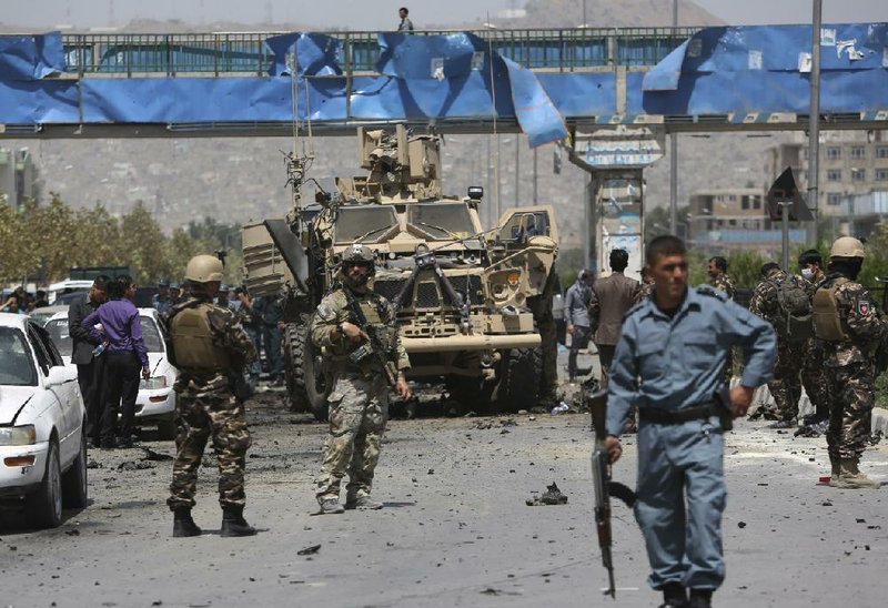 NATO and Afghan security forces stand guard at the site of a suicide attack in Kabul, Afghanistan, Sunday, Aug. 10, 2014. A suicide car bomber attacked a NATO convoy moving through Afghanistan's capital Sunday, killing several civilians and wounding more than 35 in an assault claimed by the Taliban, authorities said. (AP Photo/Rahmat Gul)