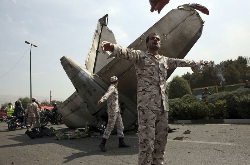 Iranian Revolutionary Guards prevent the media from approaching the wreckage of a passenger plane crash near the capital Tehran, Iran, Sunday, Aug. 10, 2014. An Iranian passenger plane crashed Sunday while taking off from an airport near the capital, Tehran, killing tens of people onboard, state media reported. (AP Photo/Vahid Salemi)
