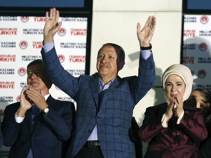 Turkish Prime Minister Recep Tayyip Erdogan, center, flanked by Kyrgyzstan President Almazbek Atambayev and his wife Emine Erdogan acknowledge supporters after Erdogan's election victory, in Ankara, Turkey, Sunday, Aug. 10, 2014. Erdogan won Turkey's first direct presidential election Sunday, striking a conciliatory tone toward critics who fear he is bent on a power grab as he embarks on another five years at the country's helm. (AP Photo/Burhan Ozbilici)