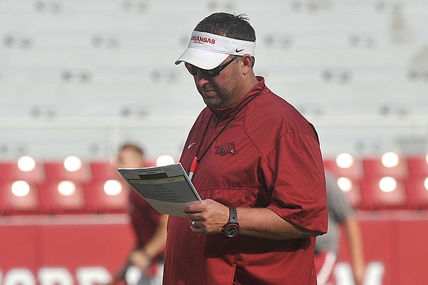 Arkansas coach Bret Bielema reads his notes during a practice Saturday, Aug. 9, 2014 at Razorback Stadium in Fayetteville. 