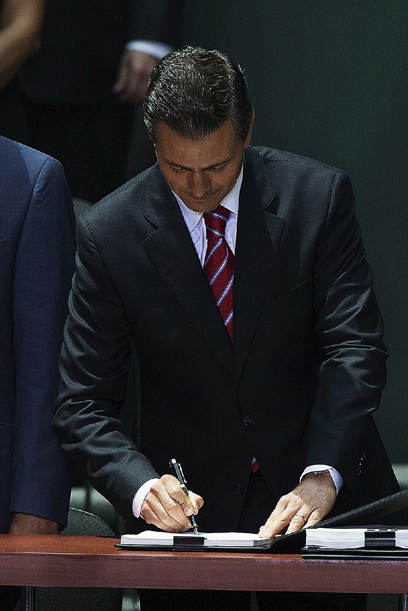 Enrique Pena Nieto, president of Mexico, signs legislation during a ceremony in Mexico City, Mexico, on Monday, Aug. 11, 2014. Pena Nieto signed legislation formally opening Mexicoís state-controlled energy industry to private investment, completing the countryís most important economic overhaul since the North American Free Trade Agreement. Photographer: Susana Gonzalez/Bloomberg *** Local Caption *** Enrique Pena Nieto