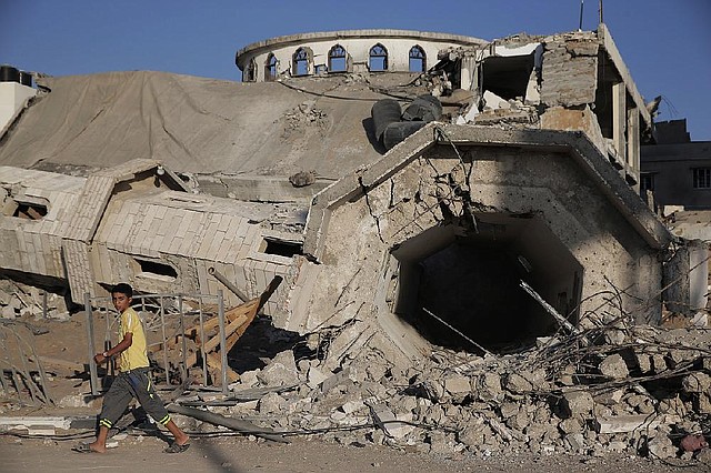 A Palestinian boy walks by the rubble of the toppled minaret of the Abu Jihad Al Wazer mosque, destroyed by an Israeli strike during the war, in Gaza City, Monday, Aug. 11, 2014. (AP Photo/Lefteris Pitarakis)