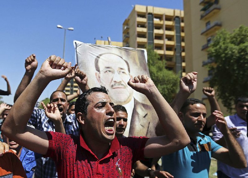 Iraqis chant pro-government slogans and display placards bearing a picture of embattled Prime Minister Nouri al-Maliki during a demonstration in Baghdad, Iraq, Monday, Aug. 11, 2014. Al-Maliki is taking his struggle to keep his job to the courts after announcing he will file a legal complaint on Monday against the country's newly elected president. President Barack Obama warned Americans on Saturday that the new campaign to bring security in Iraq requires military and political changes and "is going to be a long-term project." (AP Photo/ Hadi Mizban)