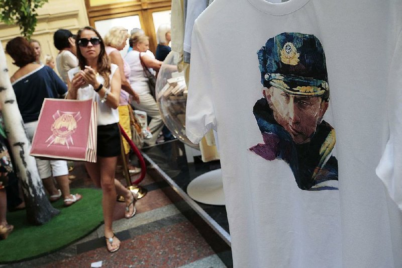 A young woman holds a bag with T-shirts with images of Russian President Putin, which she has just bought, at GUM (the State Department Store) in Moscow, Russia, Monday, Aug. 11, 2014.  Putin’s popularity in Russia has soared following his decision to annex Ukraine’s Crimean Peninsula. Putin's image is on the T-shirt at right. (AP Photo/Ivan Sekretarev)