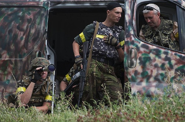 Ukrainian government soldiers from battalion "Donbass" guard their positions in village Mariinka near Donetsk, eastern Ukraine, Monday, Aug. 11, 2014. The Red Cross will lead an international humanitarian aid operation into Ukraine’s conflict-stricken province of Luhansk with assistance from Russia, the European Union and the United States, Ukraine said Monday.(AP Photo/Evgeniy Maloletka)