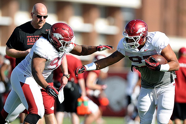 Rory Segrest, back, watches on as Darius Philon, left, tries to tackle Tevin Beanum, right, at spring football practice Tuesday, April 22, 2014, at University of Arkansas in Fayetteville.