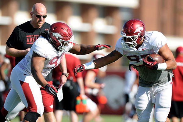 Rory Segrest, back, watches on as Darius Philon, left, tries to tackle Tevin Beanum, right, at spring football practice Tuesday, April 22, 2014, at University of Arkansas in Fayetteville.