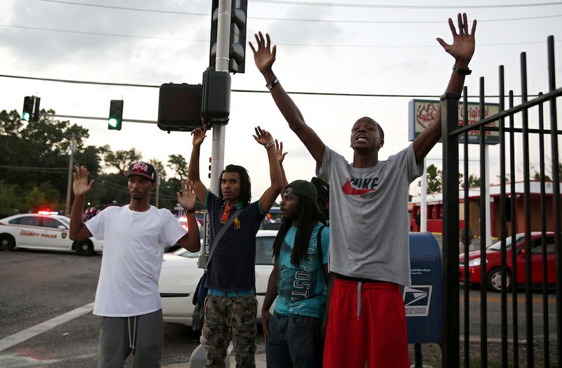 Protesters yell at police Monday, Aug. 11, 2014, in Ferguson, Mo. The FBI opened an investigation Monday into the death of 18-year-old Michael Brown, who police said was shot multiple times Saturday after being confronted by an officer in Ferguson. Authorities in Ferguson used tear gas and rubber bullets to try to disperse a large crowd Monday night that had gathered at the site of a burned-out convenience store damaged a night earlier, when many businesses in the area were looted. 