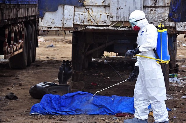 The body of a man suspected of dying in the street from the ebola virus is sprayed with disinfectant Tuesday in Monrovia, Liberia.