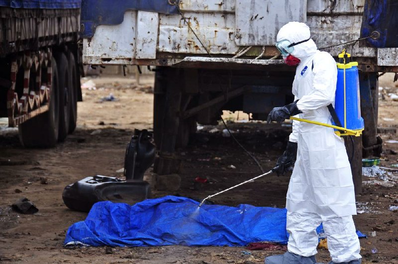 The body of a man suspected of dying in the street from the ebola virus is sprayed with disinfectant Tuesday in Monrovia, Liberia.