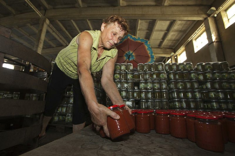 A woman places jars of tomato paste in a warehouse last week in Harbovat, Moldova. Russia banned foods from Moldova in late July, a burden on a national economy reliant on agriculture.