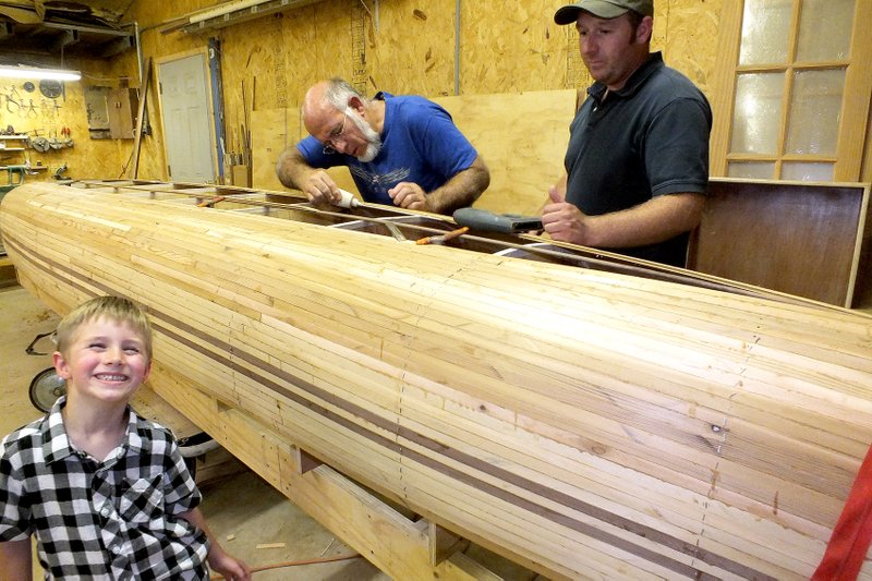 Staff Photo Annette Beard Zeke Whitaker, 5, grins about helping his father and grandfather with the second strip canoe the men are building. Zeke and his father, Josh Whitaker, took the first one out on the White River last weekend but didn&#8217;t catch any fish.