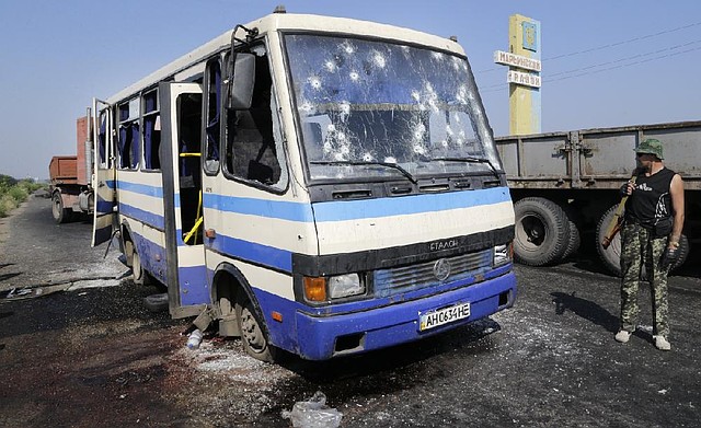 A pro-Russia fighter stands near a bullet-riddled bus Wednesday outside Donetsk in eastern Ukraine where at least 12 militiamen fighting alongside government forces were killed in an ambush.