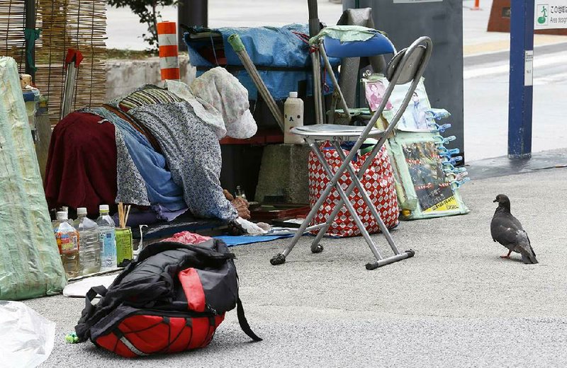 A shoeshine prepares for work Wednesday on a sidewalk in Tokyo. The Japanese economy shrank at an annual pace of 6.8 percent in the second quarter, the government said Wednesday.