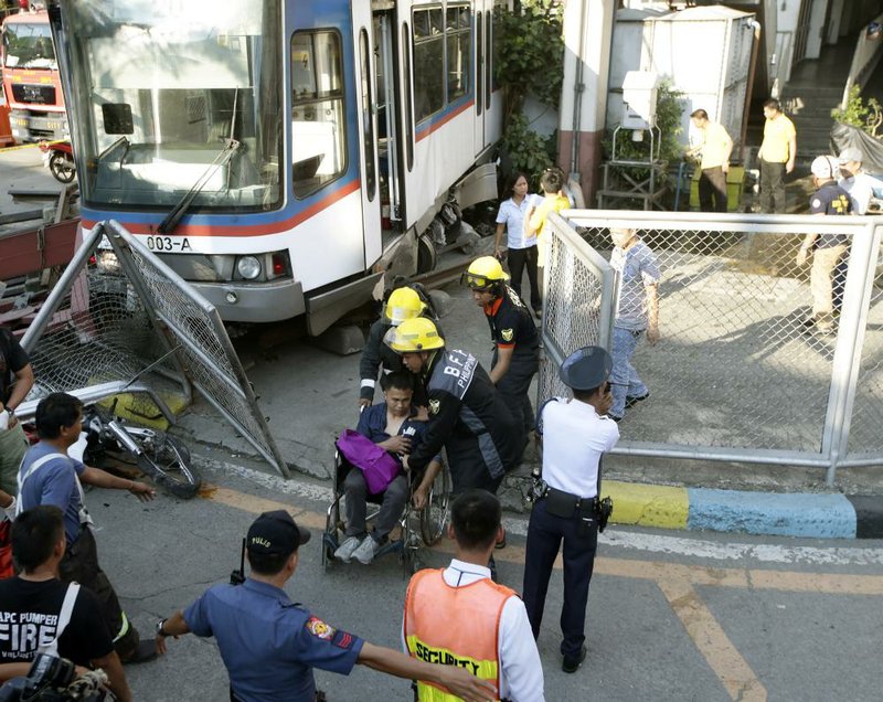 Rescuers help an injured passenger after an elevated Metro Rail Transit commuter train overshot its tracks and derailed at the end station Wednesday, injuring dozens in suburban Pasay city south of Manila, Philippines.