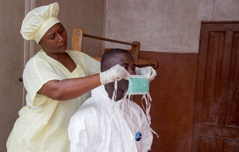 A health care worker helps a colleague as she prepares his Ebola personal protective equipment before he enters the Ebola isolation ward Tuesday at Kenema Government Hospital in Kenema, the Eastern Province, about 186 miles from the capital city of Freetown, Sierra Leone.