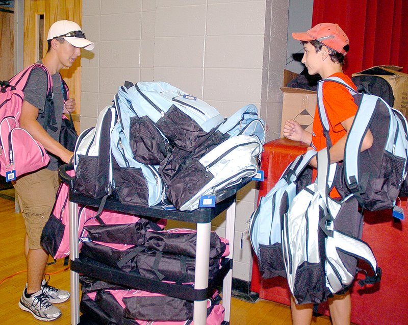 RICK PECK MCDONALD COUNTY PRESS Matthew Sedillos and Jackson Behm, volunteers from Anderson, help carry and haul some of the 650 backpacks that were given away Aug. 7 at a McDonald County United Way and Bright Futures back-to-school event. The backpacks were donated by the McDonald County Telephone Company.