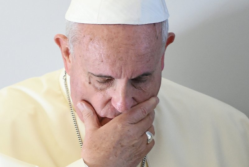 Pope Francis touches his face during his meeting with journalists aboard the papal flight on the journey to Seoul, South Korea, while he is informed by Father Federico Lombardi that Associated Press video journalist Simone Camilli, of Italy, died in Gaza, on Wednesday, Aug. 13, 2014. 