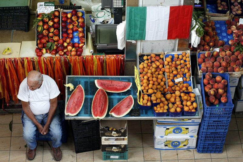 A vendor mans his fruit and vegetable stall at an indoor market in Rome on Tuesday. Gross domestic product in the euro area was unchanged in the second quarter, the European Union’s statistics office in Luxembourg said Thursday.