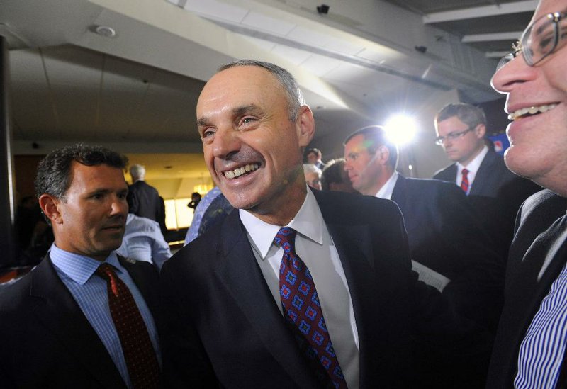 Major League Baseball Chief Operating Officer Rob Manfred, center, smiles after team owners elected him as the next commissioner of Major League Baseball during an owners quarterly meeting in Baltimore, Thursday, Aug. 14, 2014. (AP Photo/Steve Ruark)