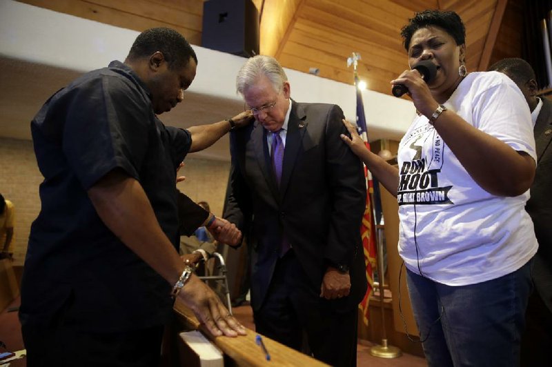 Missouri Gov. Jay Nixon (center) joins in a prayer Thursday during a meeting of clergymen and community members held in Florissant, Mo., to discuss the police response to demonstrations over the killing of 18-year-old Michael Brown.