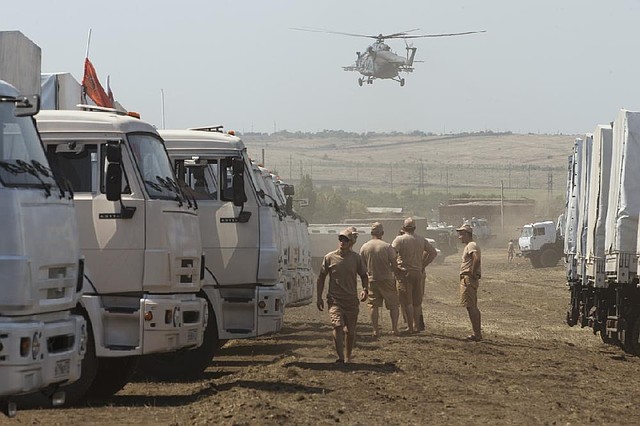 A convoy of Russian trucks carrying humanitarian aid waits in a field about 17 miles from the Ukrainian border.