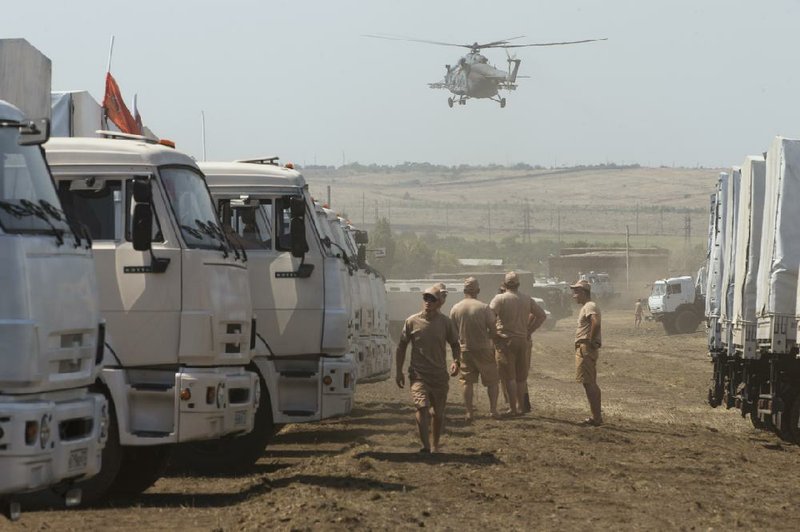 A convoy of Russian trucks carrying humanitarian aid waits in a field about 17 miles from the Ukrainian border.