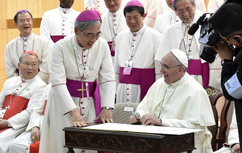 Pope Francis signs the guestbook Thursday during a meeting with South Korean bishops at the headquarters of the Korean Episcopal Conference in Seoul.