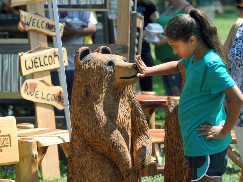 Michael Woods Photo Courtesy NWA Media Andrea Billingsley takes a closer look at a wooden bear on display at a previous Prairie Grove Clothesline Fair.