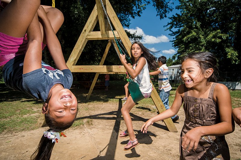 Juliana Cruz, left, Karla Rodriguez, center, and Brigett Trujillo have fun on the swings at a park under construction in the Brookside Village mobile-home community in Conway. The park is being built by City of Hope Outreach and its partners. CoHO, a nonprofit ministry, offers after-school tutoring and Bible studies for students and English as a Second Language classes for adults in the mobile-home park.