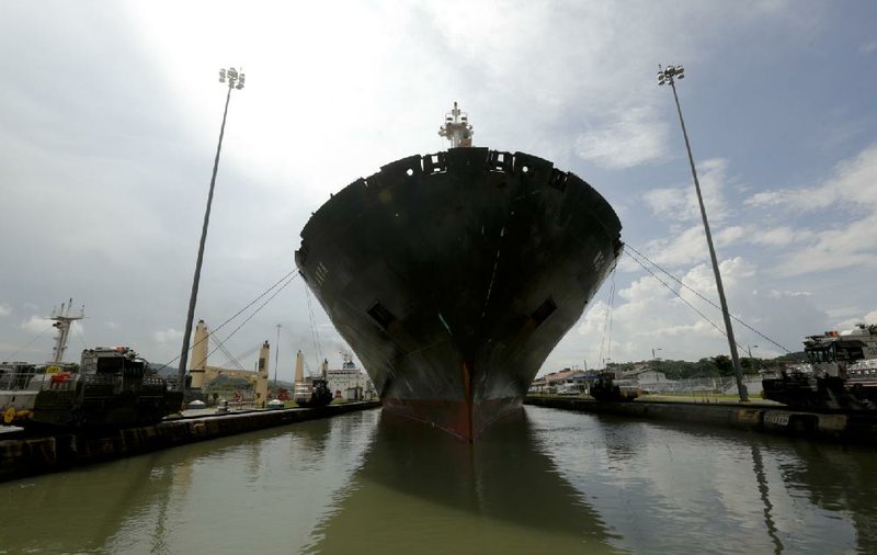 In this Aug. 4, 2014, photo, electric powered locomotives guides a vessel through the Miraflores locks of the Panama Canal in Panama City. For the most part, the canal has blossomed under Panamanian management, contributing more than $8.5 billion in government revenue since the Americans handed it over on Dec. 31, 1999. (AP Photo/Arnulfo Franco)