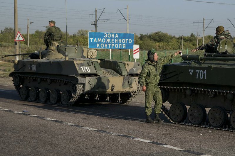 Russian solders with their several military vehicle gather at the rail road crossing about 30 kilometers (19 miles) from Ukrainian border at  Rostov-on-Don region, Russia, early Friday, Aug. 15, 2014. The sigh reads "Customs control zone". (AP Photo/Pavel Golovkin)