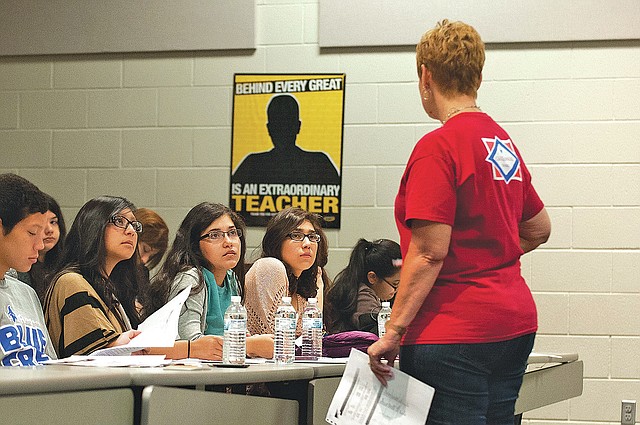 STAFF PHOTO Spencer Tirey Israel Garcia, from left, looks at a list of words as Hisleny Gracia, Diana Olvera and Aneli Perez listen Friday to teacher Jeanette Arnhart speak during an ACT preparatory class a Heritage High School in Rogers. Students at La Academia ACT are combining strengths in biliteracy with more traditional ACT test preparation.