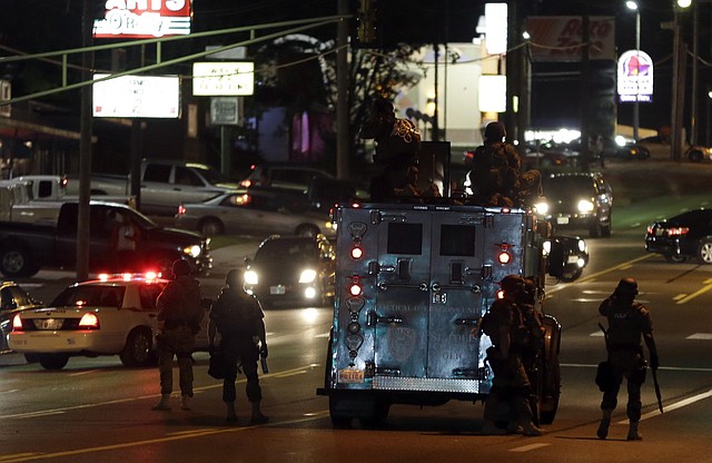 Police attempt to secure a street after a clash with protesters Wednesday, Aug. 13, 2014, in Ferguson, Mo.  Protests in the St. Louis suburb rocked by racial unrest since a white police officer shot an unarmed black teenager to death turned violent Wednesday night, with people lobbing molotov cocktails at police who responded with smoke bombs and tear gas to disperse the crowd.