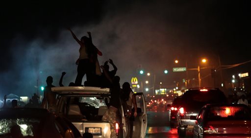 Smoke from a tire burnout rises over protestors on West Florissant Avenue in Ferguson on Friday, Aug. 15, 2014.