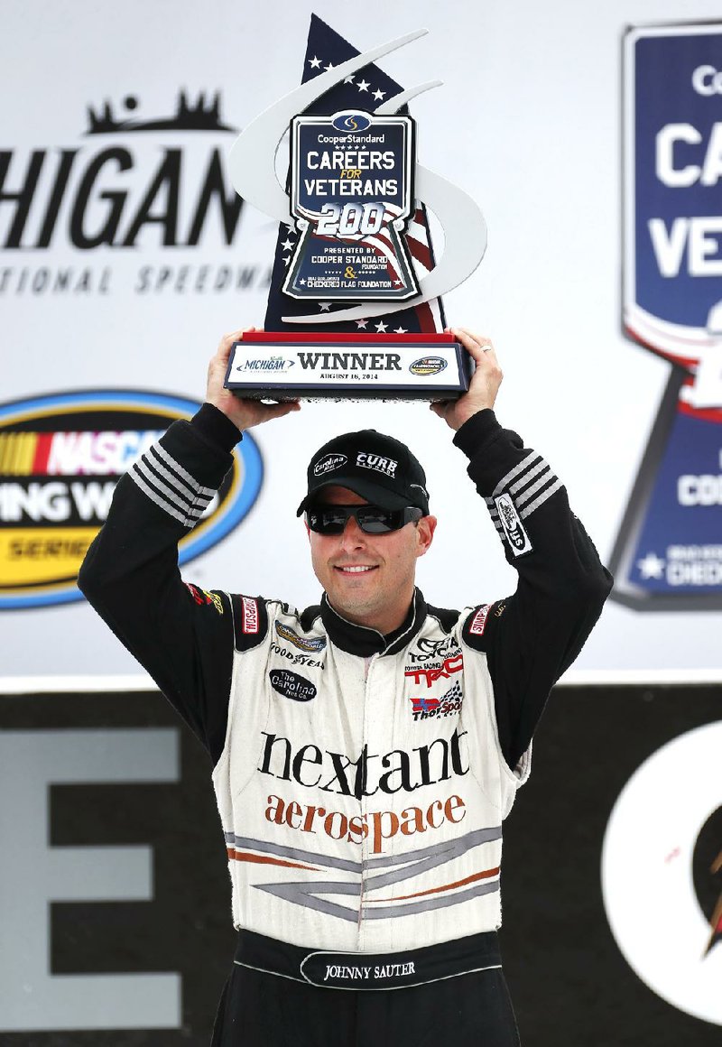 Johnny Sauter holds up the trophy in Victory Lane after winning the NASCAR Camping World truck series auto race at Michigan International Speedway in Brooklyn, Mich., Saturday, Aug. 16, 2014. (AP Photo/Bob Brodbeck)