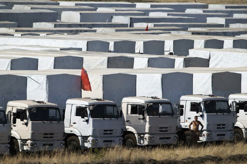 A driver stands Saturday in front of trucks that are part of an aid convoy parked near the Ukrainian border.