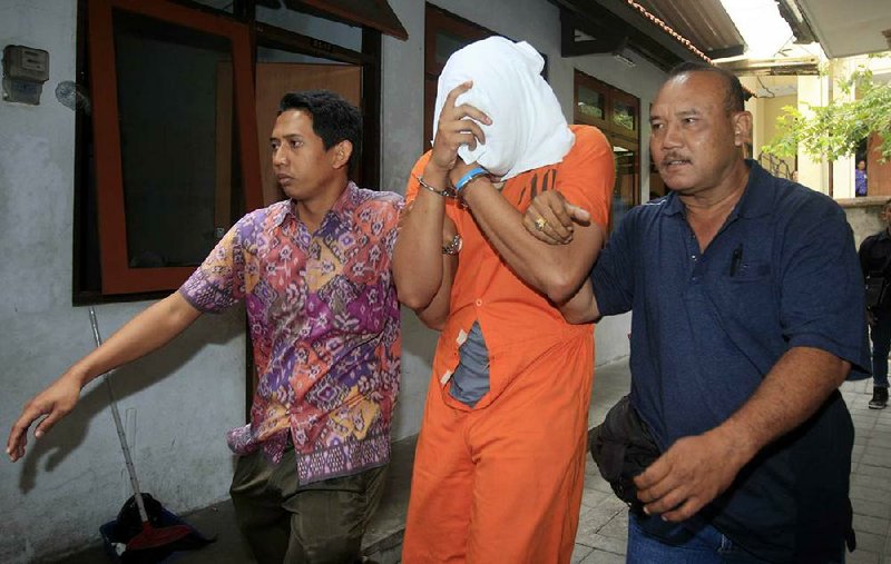 Indonesian police officers escort a face-covered Tommy Schaefer to a hospital Friday for a medical check. Schaefer and his girlfriend were arrested last week in the slaying of the girlfriend’s mother in Bali.