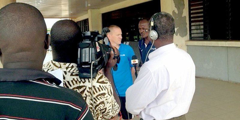 Photo courtesy of JBU Sports Information John Brown University cross country coach Scott Schochler is interviewed by a TV crew during his mission trip to Togo in West Africa. This summer was Schochler&#8217;s third trip to the country as a team leader through the organization Athletes in Action.