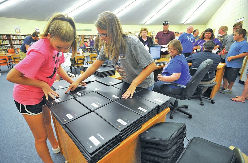 STAFF PHOTO Michael Woods &#8226; @NWAMICHAELW Tori Seaman, left, and Nicole DeSoto, both West Fork High School seniors, help pass out new Chromebooks to freshmen during orientation at the school.